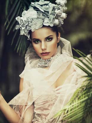Fashion model with elegant pink dress and flowers on her head in tropic forest