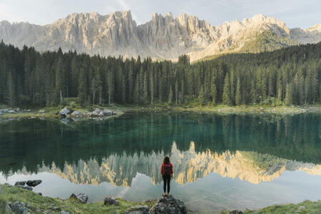 Young Caucasian woman standing and looking at  Lago di Carezza in Dolomites