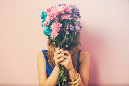 Young attractive beautiful woman smelling flowers.