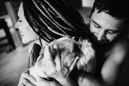 Young positive hipster couple holding a shaggy dog, and smiling. Jack Russell Terrier.Love story concept. Black and white