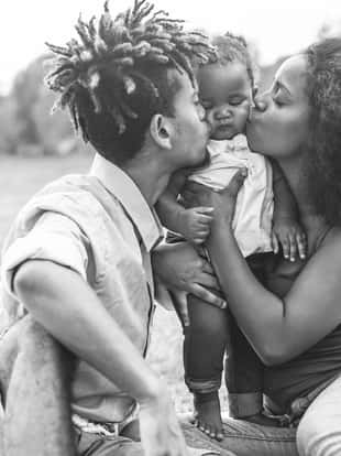 Happy black family having fun doing picnic outdoor - Parents and their daughter enjoying time together in a weekend day - Love, tender moment and happiness concept - Focus on woman face