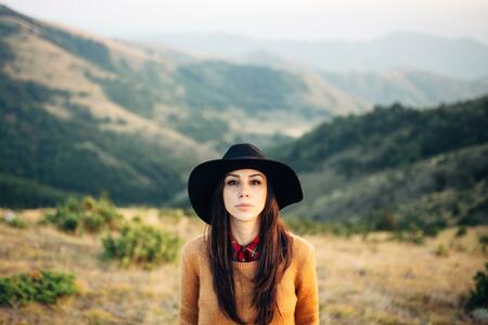 Beautiful female tourist in the sweater looking at camera and standing at the beautiful mountain scenery