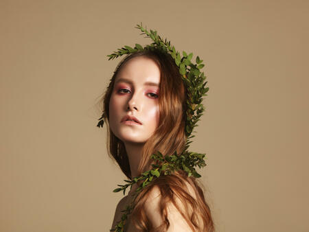 Portrait of young natural woman with green leaves in her hair