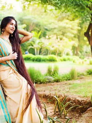 Beautiful indian woman with very long hair wearing saree in a park
