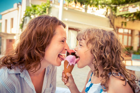 Mother and child eating ice-cream in summer cafe outdoors